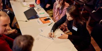 People sitting around table and writing on paper